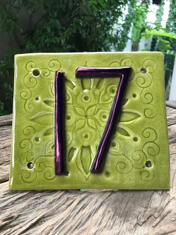 Apple green ceramic house number tile with purple metallic number seventeen and embossed floral patterns.