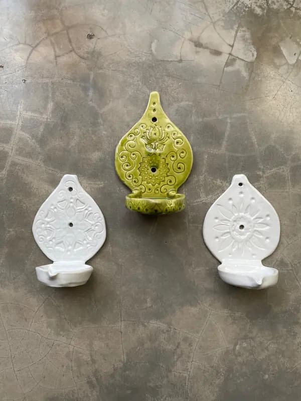 Three teardrop-shaped ceramic wall sconces in white and green with intricate embossed floral and mandala designs.
