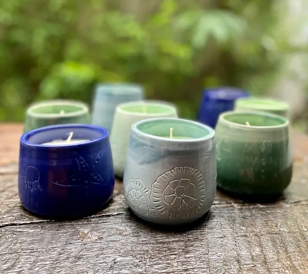 Small ceramic candle holders in blue and green glazes with carved starfish and sand dollar designs.