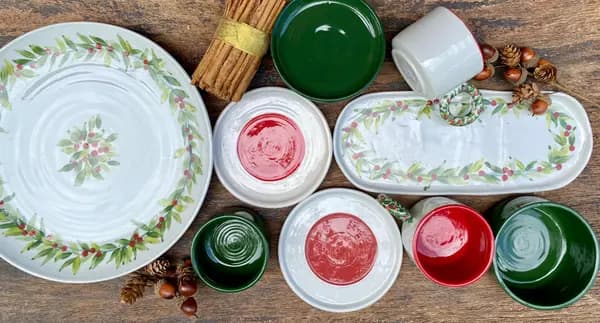 Festive ceramic tableware featuring holly leaf and red berry designs, dark green bowls, and red-glazed accents.