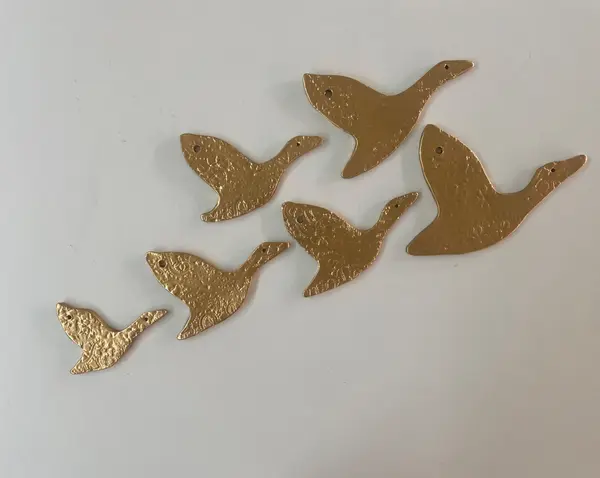 Six gold metallic ceramic birds with lace-imprinted textures, arranged as wall decorations.