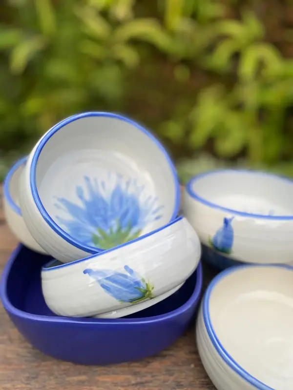 Stacked white dip bowls with blue cornflower designs, cobalt rims, and one solid cobalt bowl on a wooden surface.