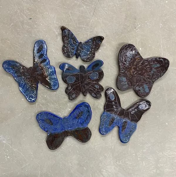 Six ceramic butterfly wall decorations in dark brown and cobalt blue glazes.
