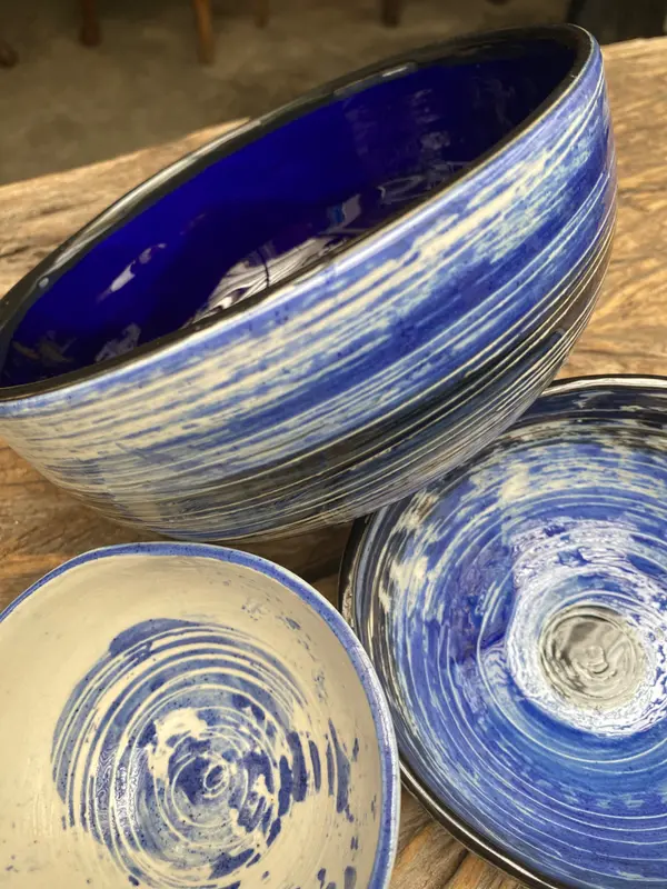 Three cobalt blue and white ceramic bowls with swirled and striped glaze patterns on a wooden surface.