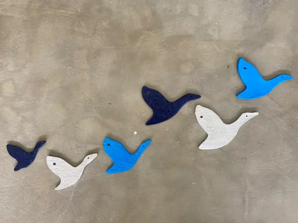 Six ceramic bird-shaped wall decorations in cobalt, light blue, and textured white glazes arranged in flight.