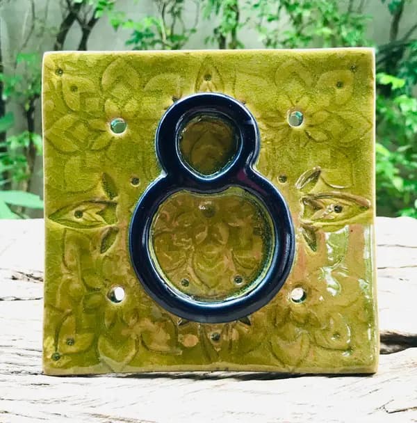 Square apple green ceramic tile with a raised floral relief and a glossy cobalt blue number eight.