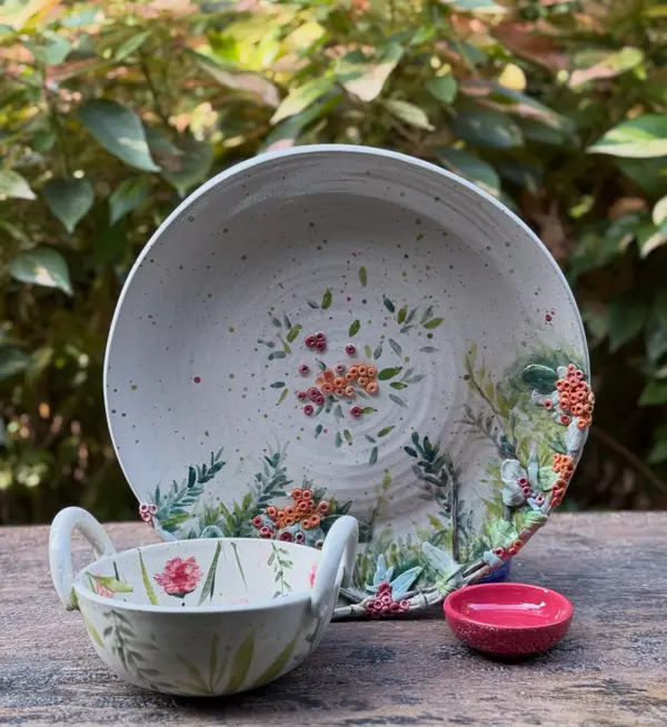 Hand-painted ceramic platter, handled bowl, and red dip bowl featuring sculpted floral and berry motifs.