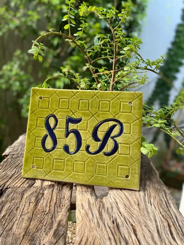 Square light green ceramic house number tile with dark blue 85B on a textured geometric background.