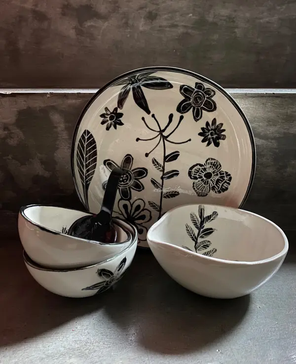 White ceramic plate and bowls set with hand-painted black floral illustrations and a glossy finish.
