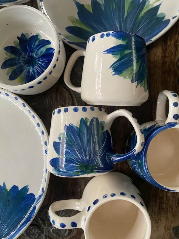 White ceramic mugs, bowl, and plate with hand-painted cobalt blue floral motifs and dots.