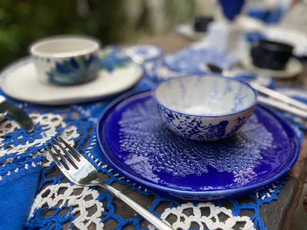 Cobalt blue plate and speckled ceramic bowl on a blue and white crochet placemat.