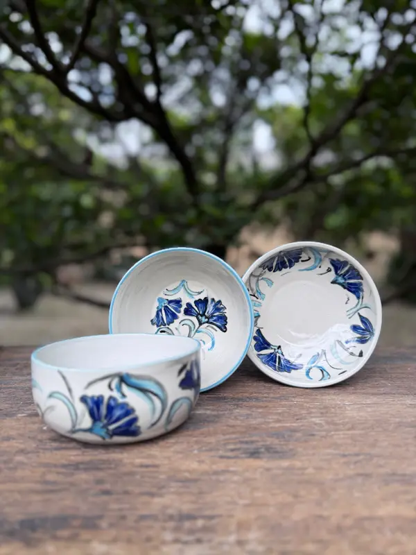 Three white ceramic bowls with hand-painted cobalt and light blue flowers on a wooden table.