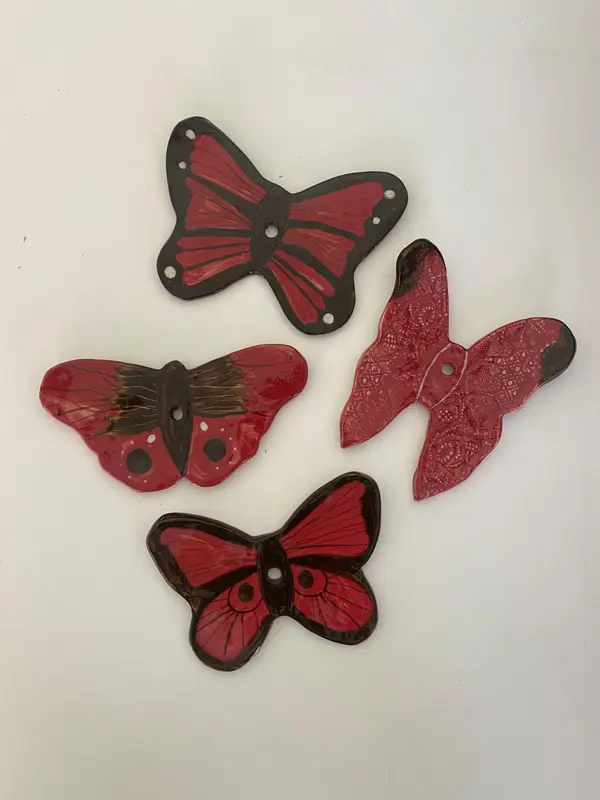Four ceramic butterfly wall decorations with glossy red and black glazes and hand-painted wing patterns.