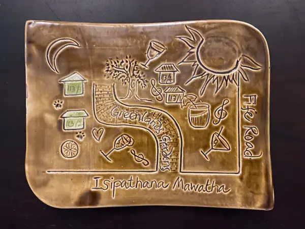 Rectangular beige ceramic plate with incised map illustrations, houses, and street names in a glossy brown glaze.