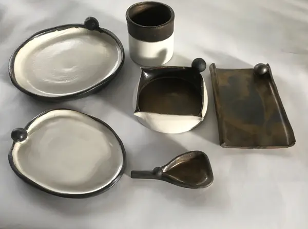 Collection of black and white ceramic dishes and a cup featuring small ball-shaped accents on the rims.