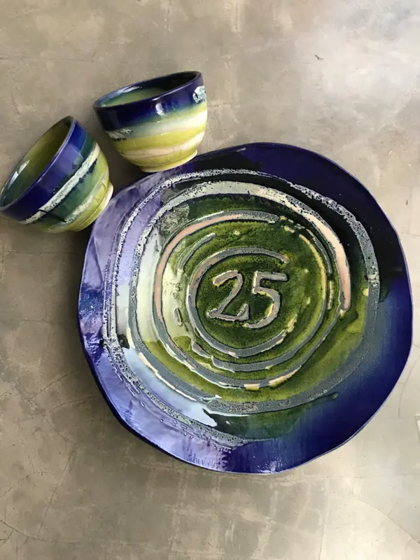 Ceramic platter and two bowls with concentric cobalt and green glazes, the platter featuring the number 25.
