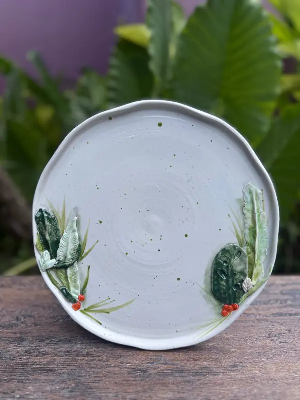 White ceramic plate with green speckles, featuring 3D sculpted green leaves and red berries at the edges.
