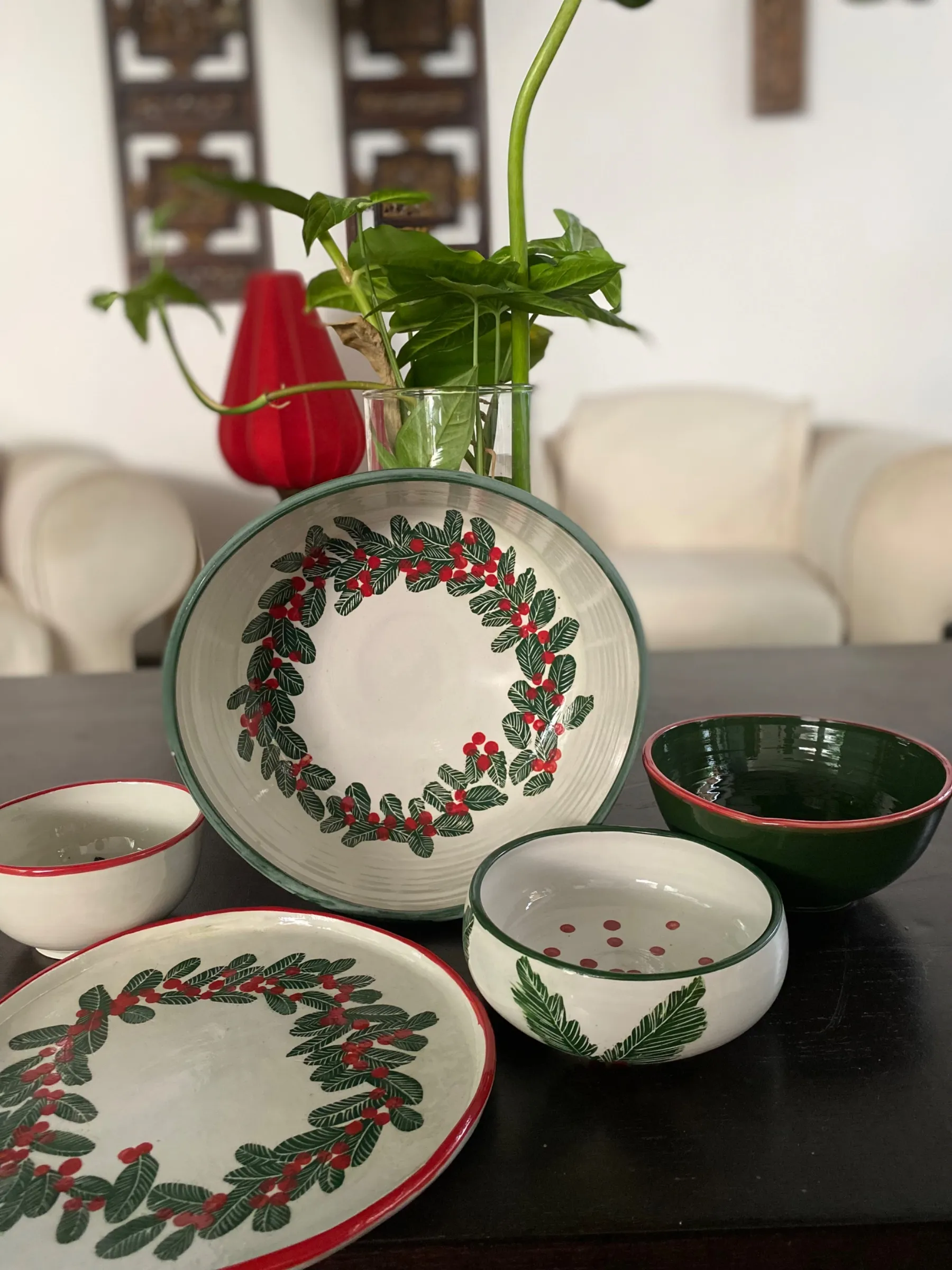 Hand-painted ceramic bowls and plate featuring a festive green wreath and red berries on a white glaze.